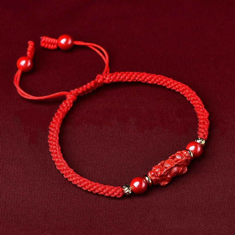 Handcrafted Pixiu cinnabar wealth bracelet flat lay featuring red woven rope and beads