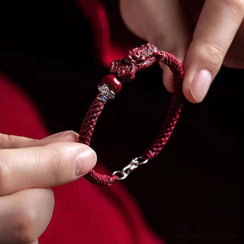 Adjustable red braided Pixiu cinnabar bracelet worn on wrist showing carved charm