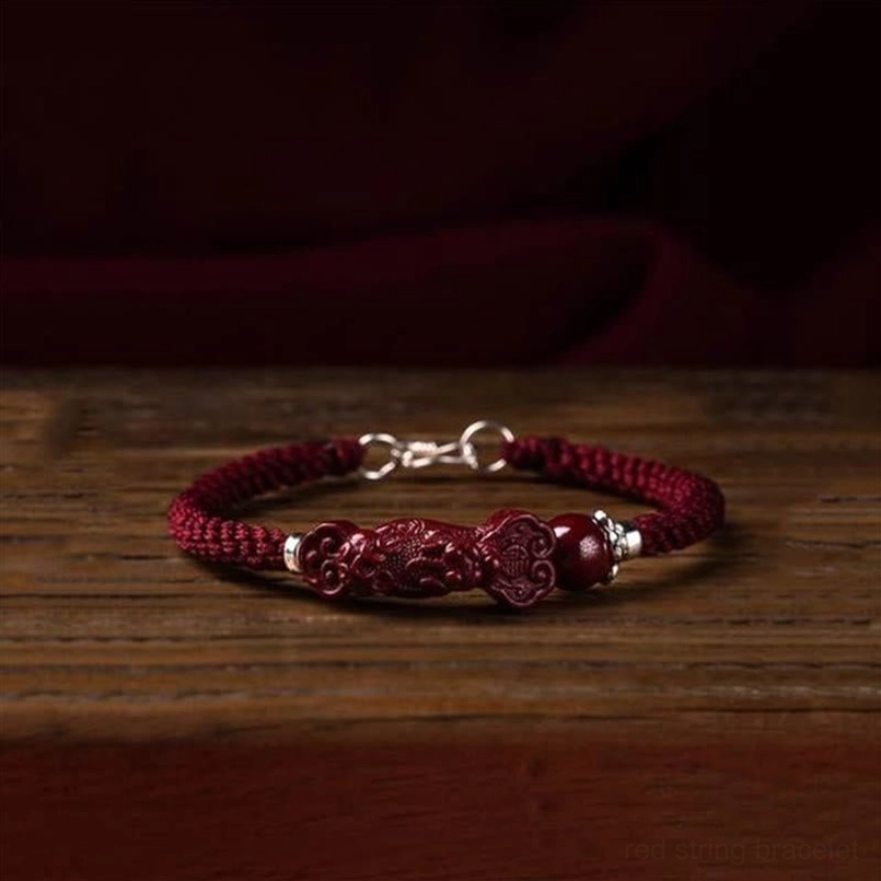 Pixiu cinnabar wealth bracelet flat lay on wooden surface with loose cinnabar accents