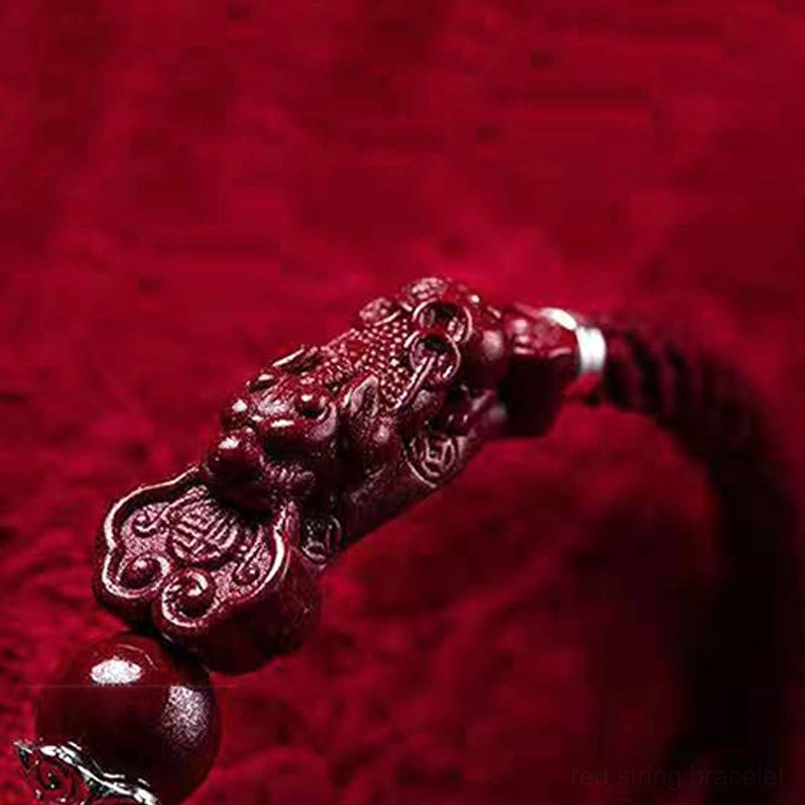 Close-up macro view of carved Pixiu charm and cinnabar bead with silver detail