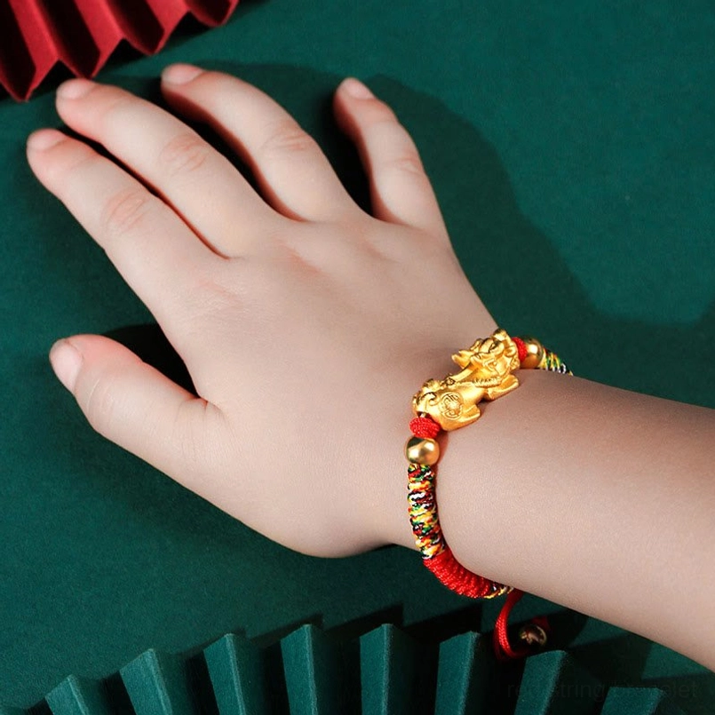 Gold-plated Pixiu kids bracelet worn on child's wrist with multicolor braided cord