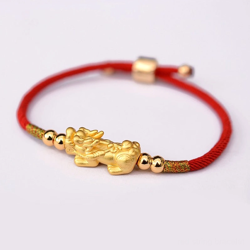Red string Pixiu bracelet with gold accent beads and sliding adjuster on white