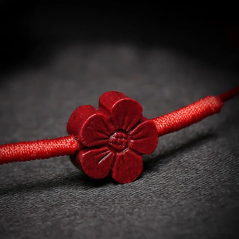 Close-up macro view of carved plum blossom charm on red string