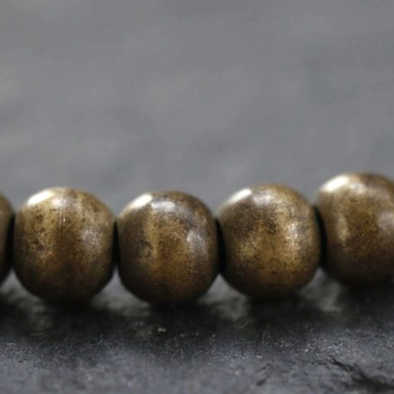 Extreme close-up of smooth matte copper brass beads on red string bracelet