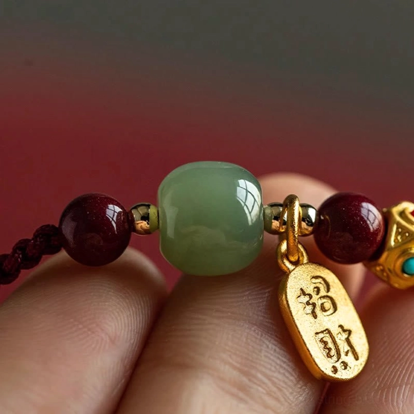 Close-up of zhao cai gold pendant charm with jade beads on five-colored braided string