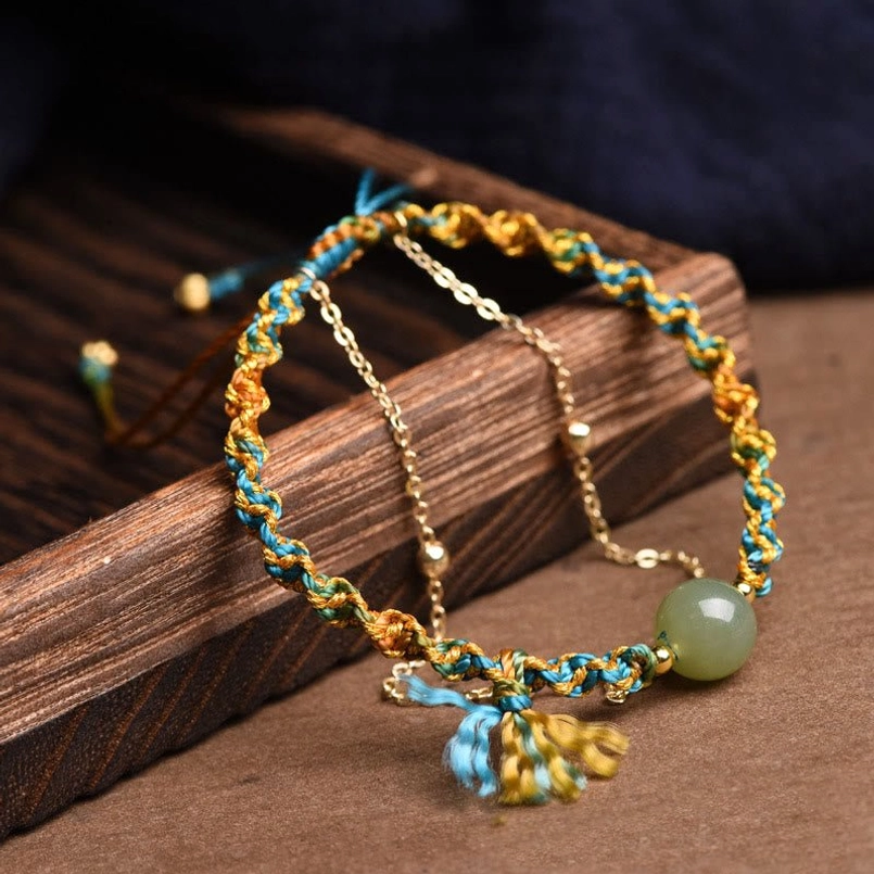 Handmade jade bracelet close-up detail showing braided rope, jade bead and metal chain accent