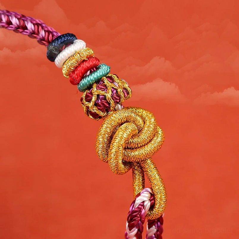 Close-up detail of golden hand-tied knot with colorful accent beads on protection bracelet