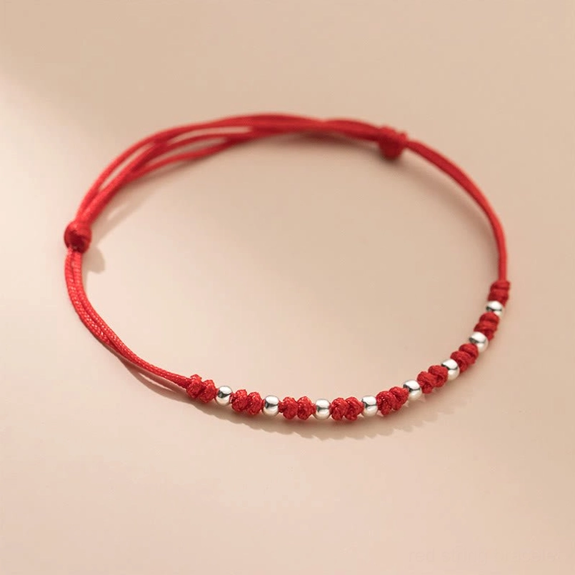 Red string silver bead bracelet front view with red knot spacers on light neutral background