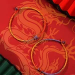 Purple gold red braided Tibetan string bracelet overhead view with dragon pattern backdrop