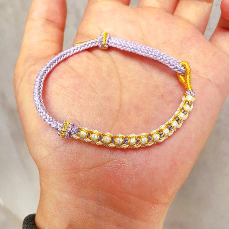 Purple Tibetan peach blossom knot red string bracelet worn on human palm closeup view