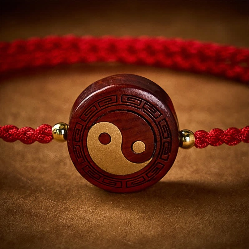 Close-up macro view of engraved yin yang charm with gold inlay and natural red braided string