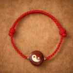 Purple sandalwood yin yang red string bracelet with gold spacer beads, top view on kraft paper