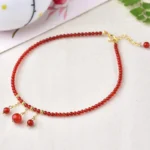 Red agate confidence calm anklet flat lay with gold hardware and dangling agate pendants