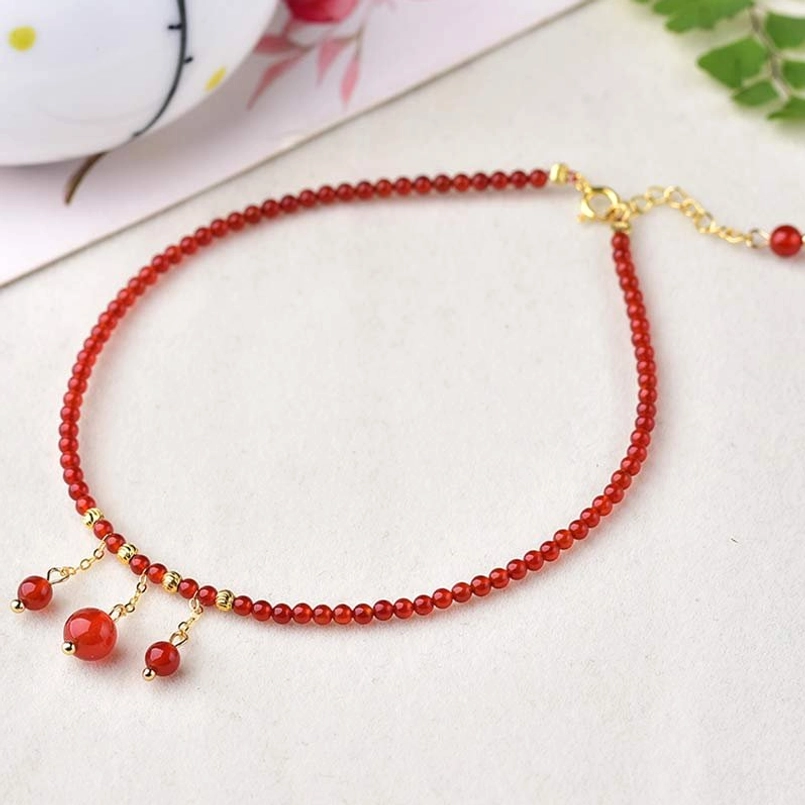 Red agate confidence calm anklet flat lay with gold hardware and dangling agate pendants