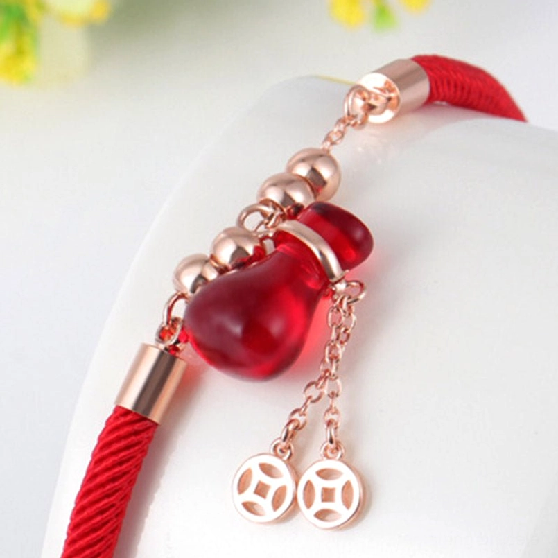Close-up detail of red agate charm and rose gold beads on red cord bracelet