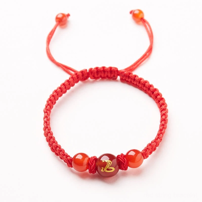 Adjustable red string bracelet featuring red agate zodiac bead flat lay display