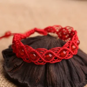 Red agate woven red string bracelet overhead view on linen wooden backdrop