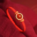 Red Agate Peace Buckle Red String Bracelet Close Up On Red Fabric Background