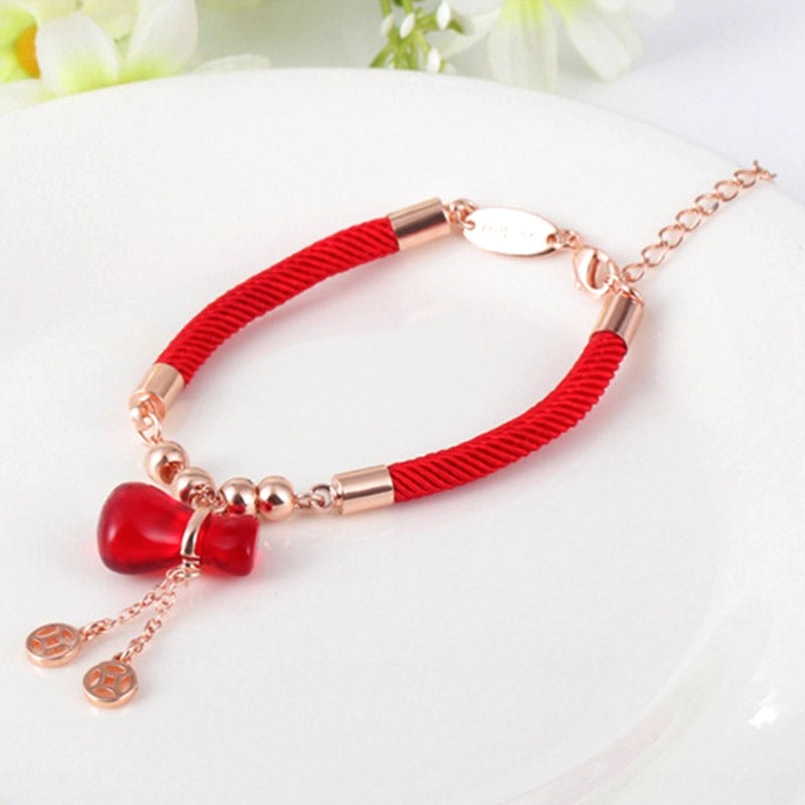 Red agate prosperity bracelet with rose gold hardware on white circular plate, overhead side view