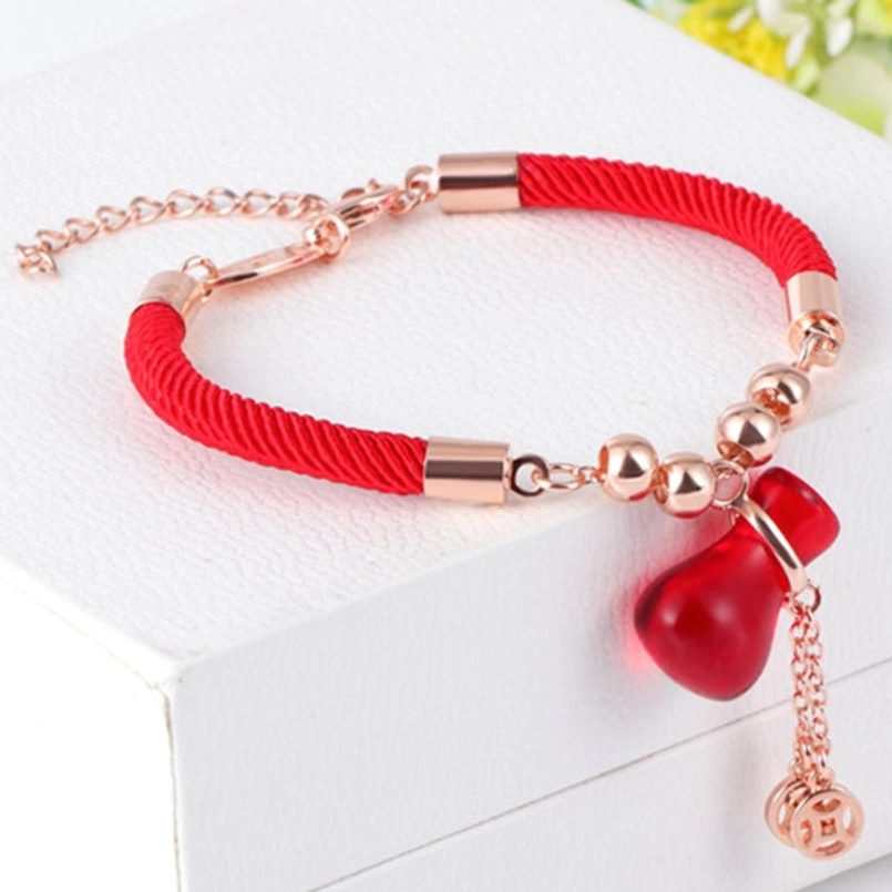 Handmade red string red agate bracelet on white jewelry display box, three-quarter angle view