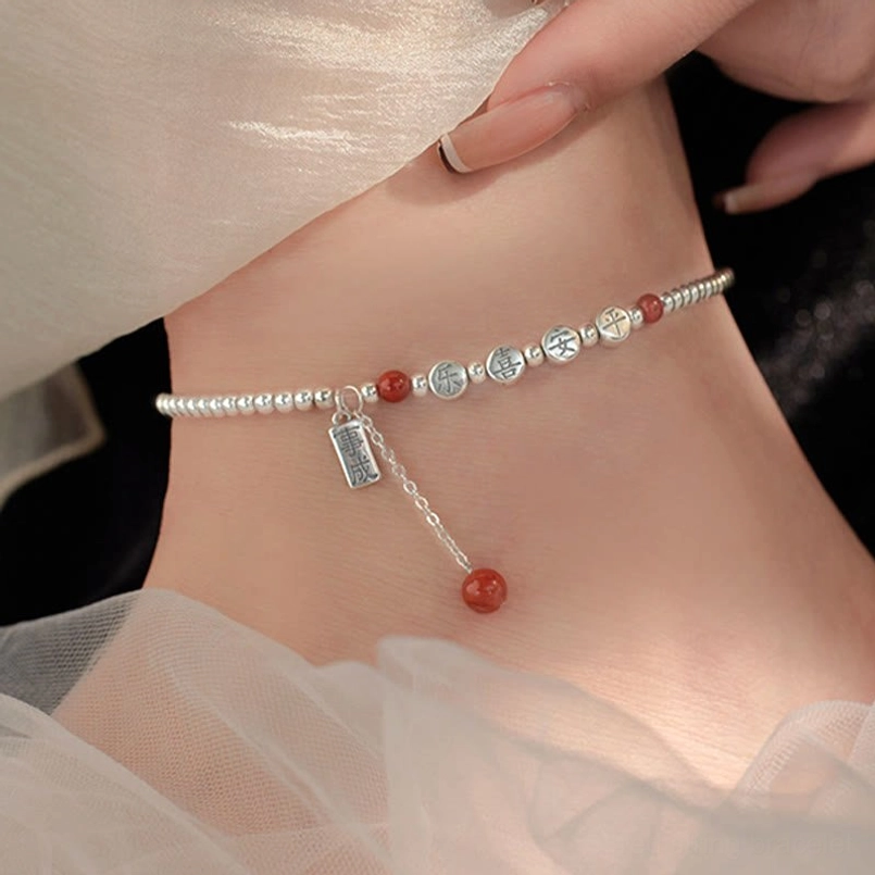 Dainty red agate and silver blessing anklet being worn on ankle with sheer white fabric backdrop