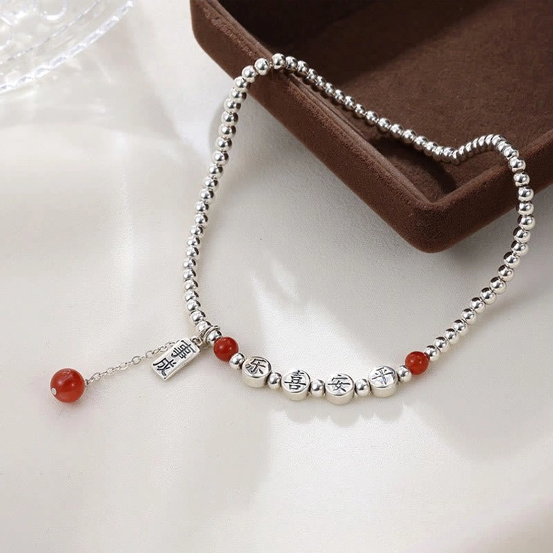 Close-up detail of red agate beads and silver charm on brown jewelry display tray