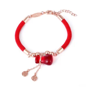 Red Agate wealth bracelet with rose gold coin pendant and braided red string, flat lay front view