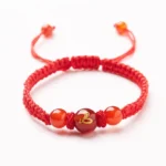 Red agate Chinese zodiac bracelet with braided red cord and adjustable knots on white background