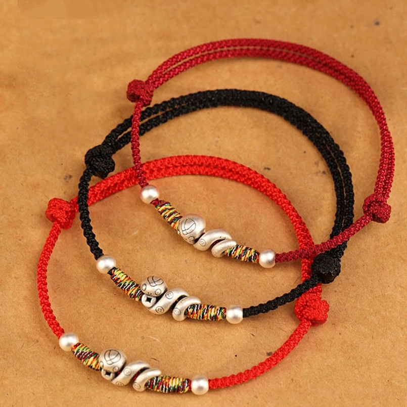 Flat lay comparison of multiple red and black string anklets with matching sterling silver snake charm designs and adjustable knots