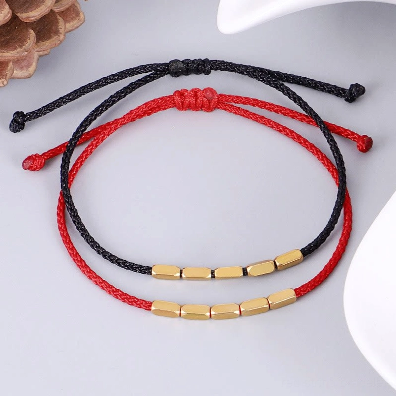 Red and black copper bead bracelets with natural pine cone decor, flat lay style