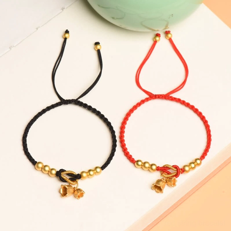Red and black woven lucky bracelets with lily charms and gold beads together