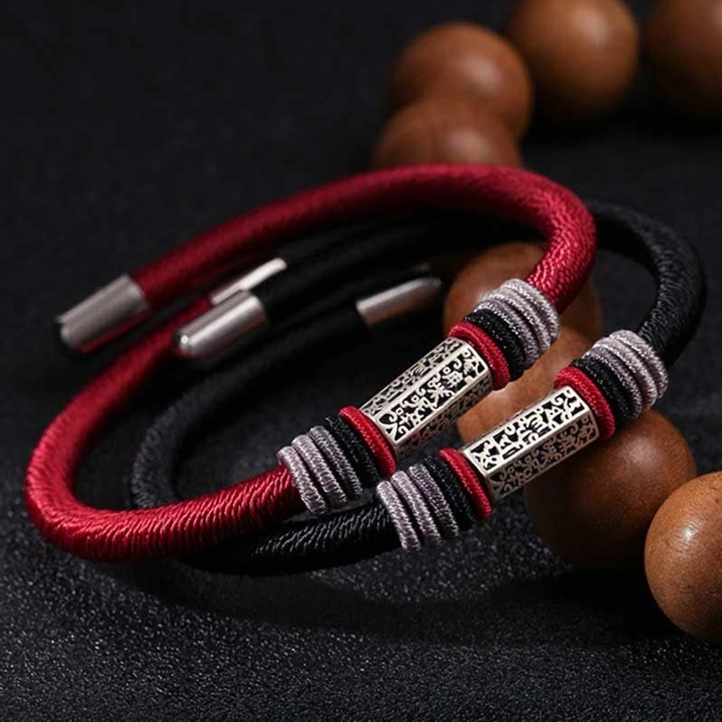 Red and black cord bracelets with matching 925 silver Om Mani Padme Hum charms, flat lay styling