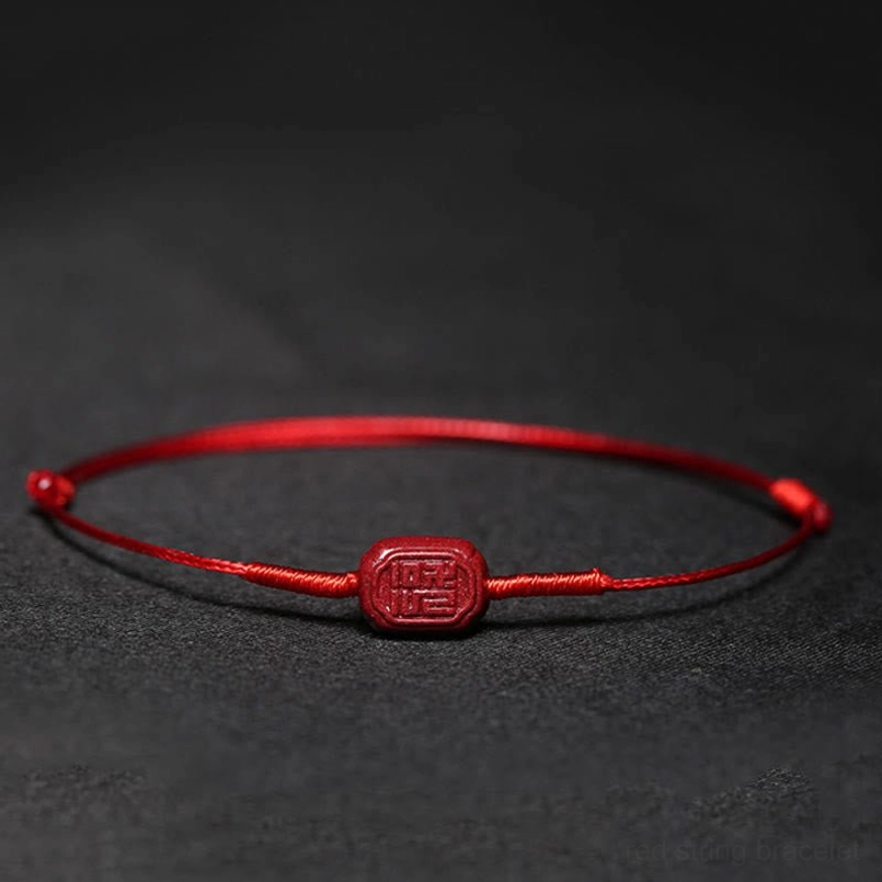 Red cord bracelet with fu auspicious character charm flat lay