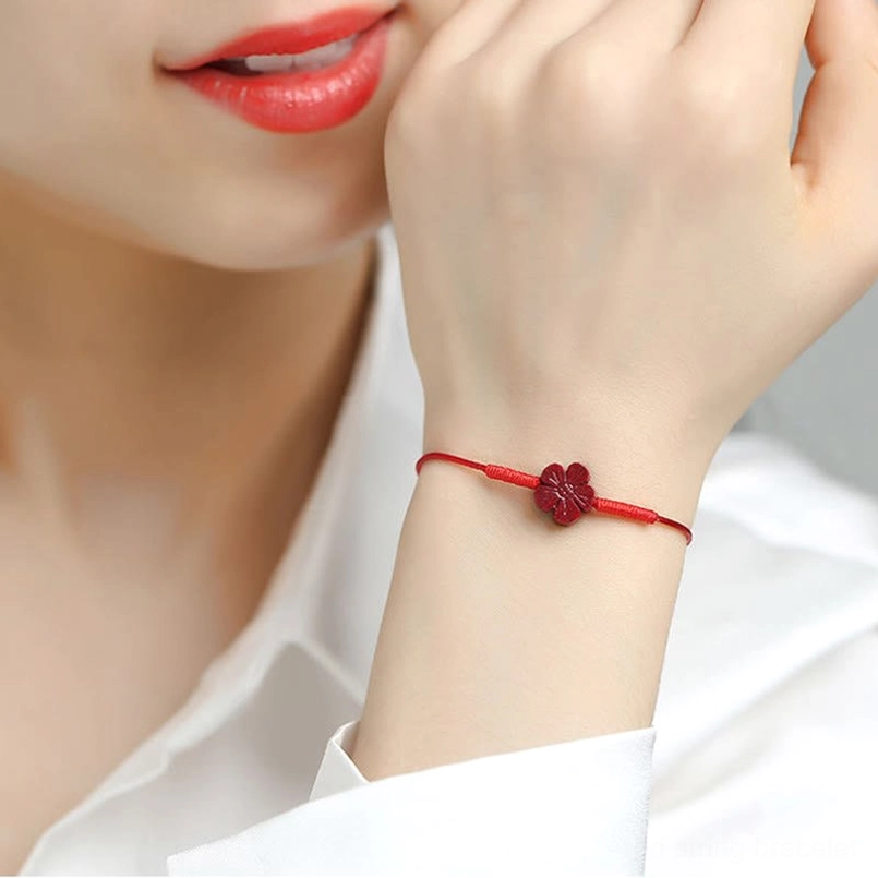 Red string bracelet with plum blossom worn on model wrist