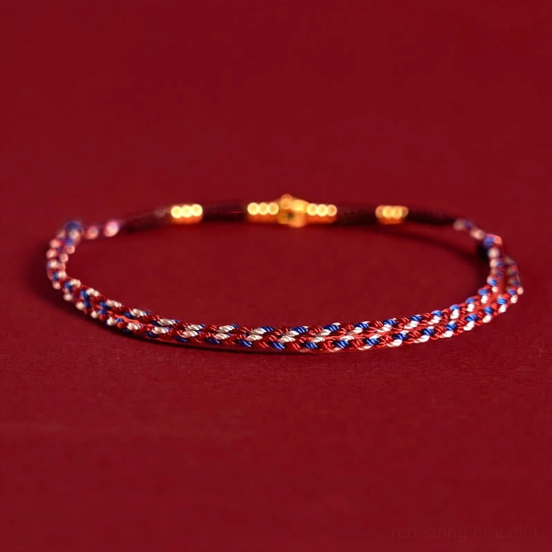 Red and blue woven string bracelet with gold decorative beads, front facing flat lay display