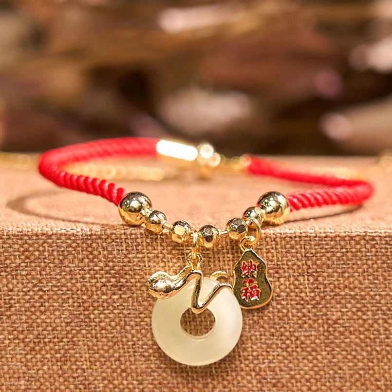 Close-up detail of red string bracelet jade peace buckle and fu charm attachments