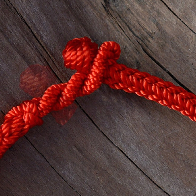 Close-up macro detail of red braided string bracelet knot closure
