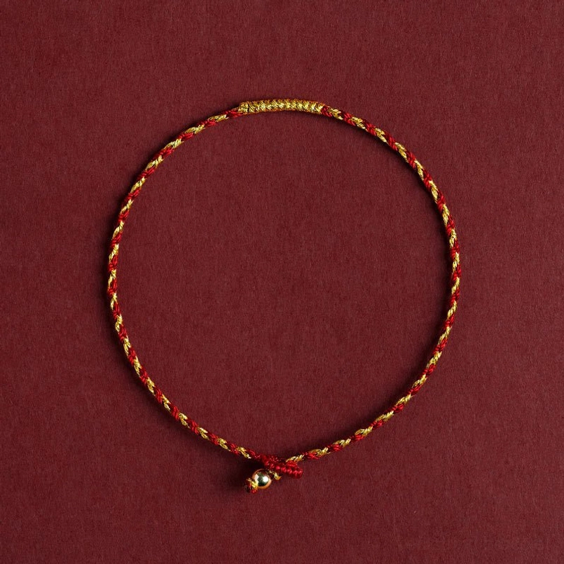 14K gold plated red braided luck bracelet with King Kong knot, top-down flat lay view