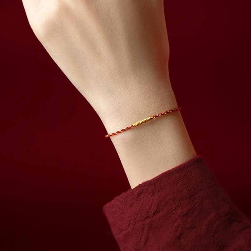 Red and gold braided luck bracelet worn on wrist, close-up side view