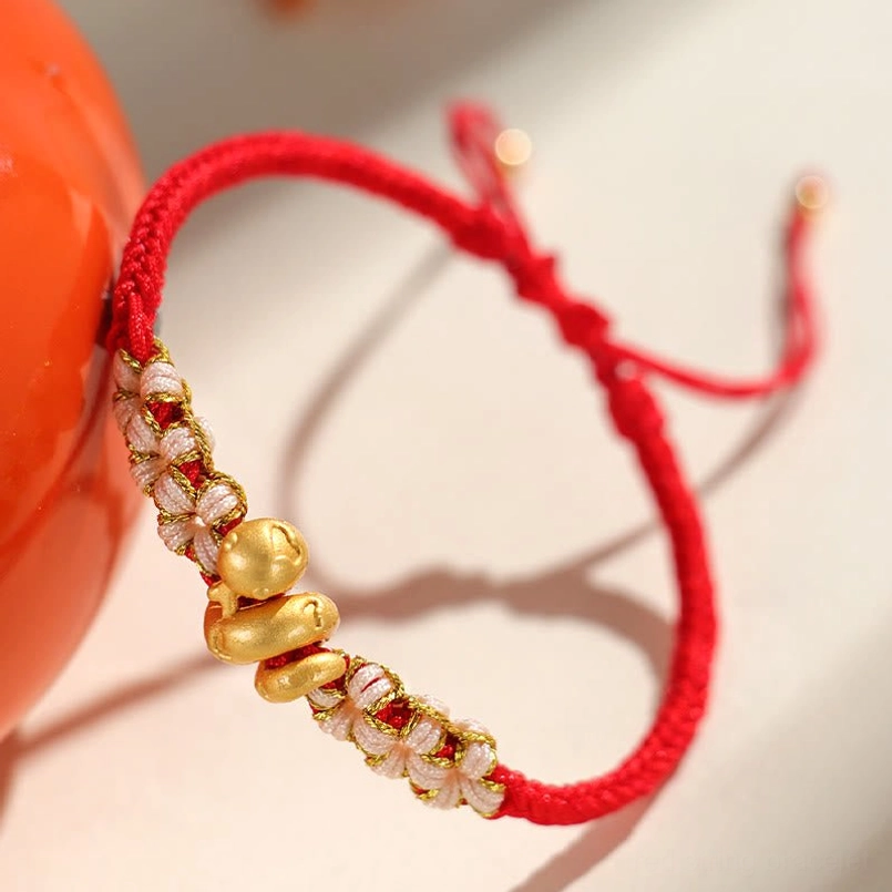 Low angle side view of red braided luck bracelet with woven peach blossom details