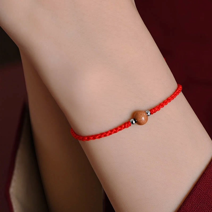 Red braided peach wood luck bracelet with natural materials - spiritual talisman close-up