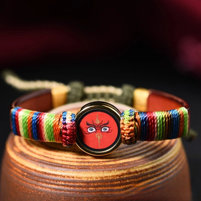 Red Buddha eye Tibetan blessing bracelet with polished gold frame and woven details