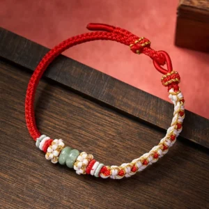 Red Chinese knot jade bracelet with peach blossom details handmade on wooden surface