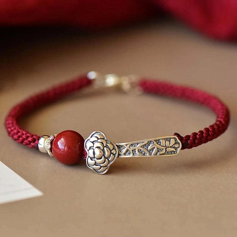 Red braided string cinnabar blessing bracelet with silver Ruyi charm close-up side view