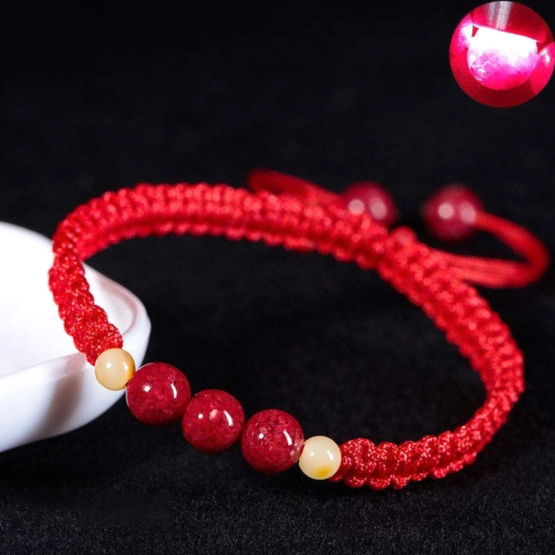 Red cinnabar string kids bracelet with braided rope and light yellow accent beads, studio flat lay