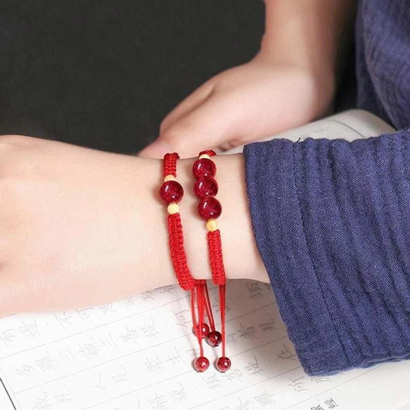 Stacked red cinnabar bracelets worn on child's wrist, dual layered design with small beads