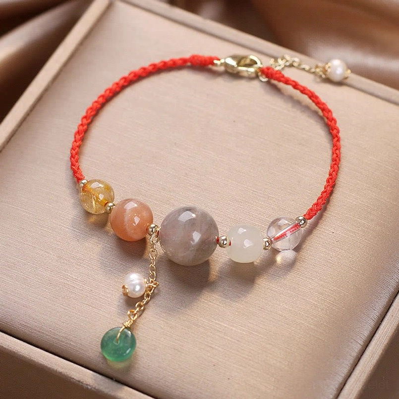 Red cord moonstone healing bracelet with adjustable extender chain and pearl decoration on display