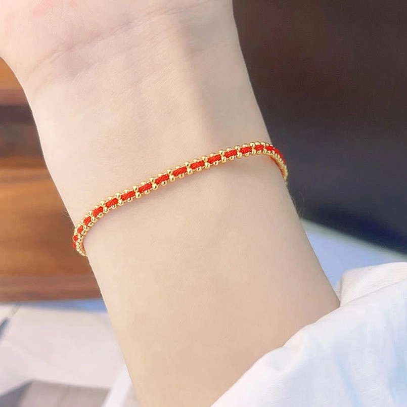 Red and gold beaded red string bracelet worn on wrist close up