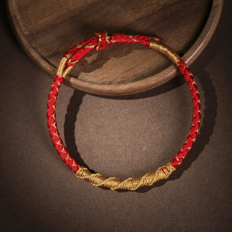 Red gold braided Tibetan protection bracelet with twisted rope design and gold accents flat lay