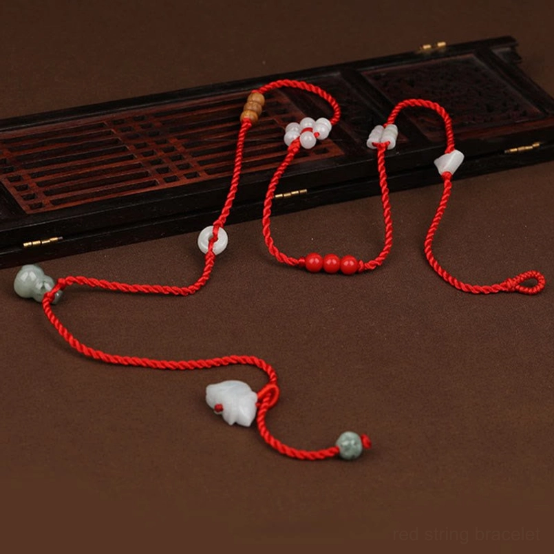 Red jade belly chain flat lay with wooden beads and jade animal pendant on antique wood tray